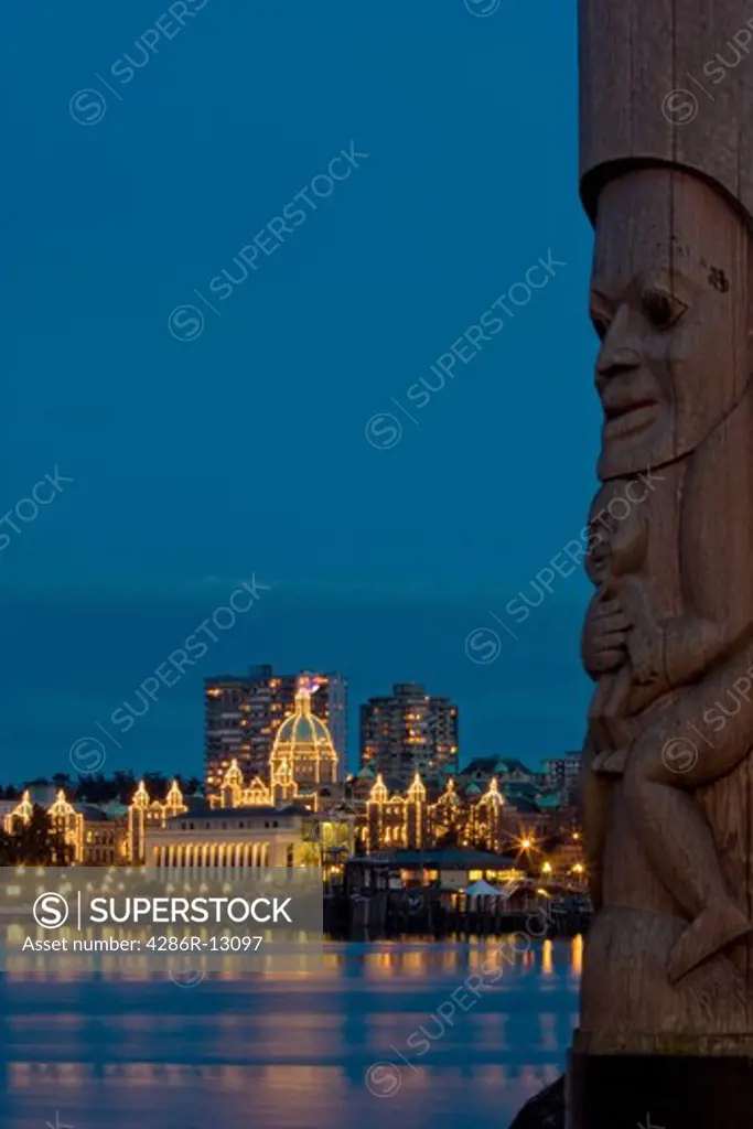 Inner harbour and Parliament Buildings at dusk - Victoria, BC, Canada. Totem pole in the foreground