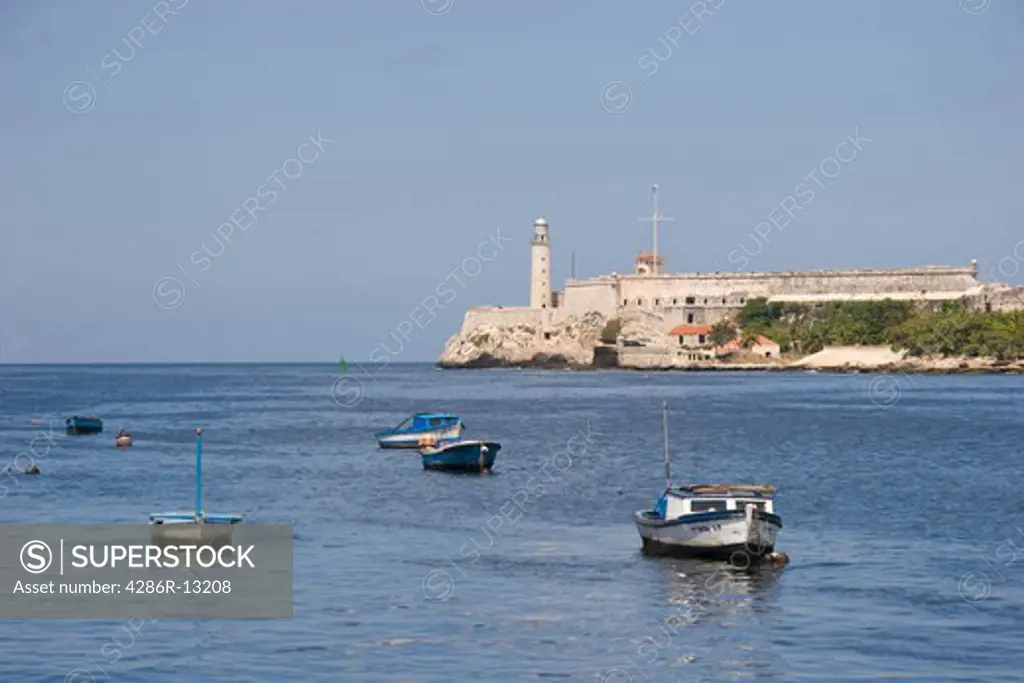 Small fishing boats dot the harbour entrance in front of the old lighthouse and citadel at the end of the Malecon, Old Havana
