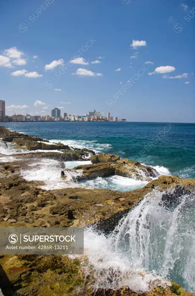 Waves crash along the Malecon in Old Havana. Centro Habana and Vedado are in the background