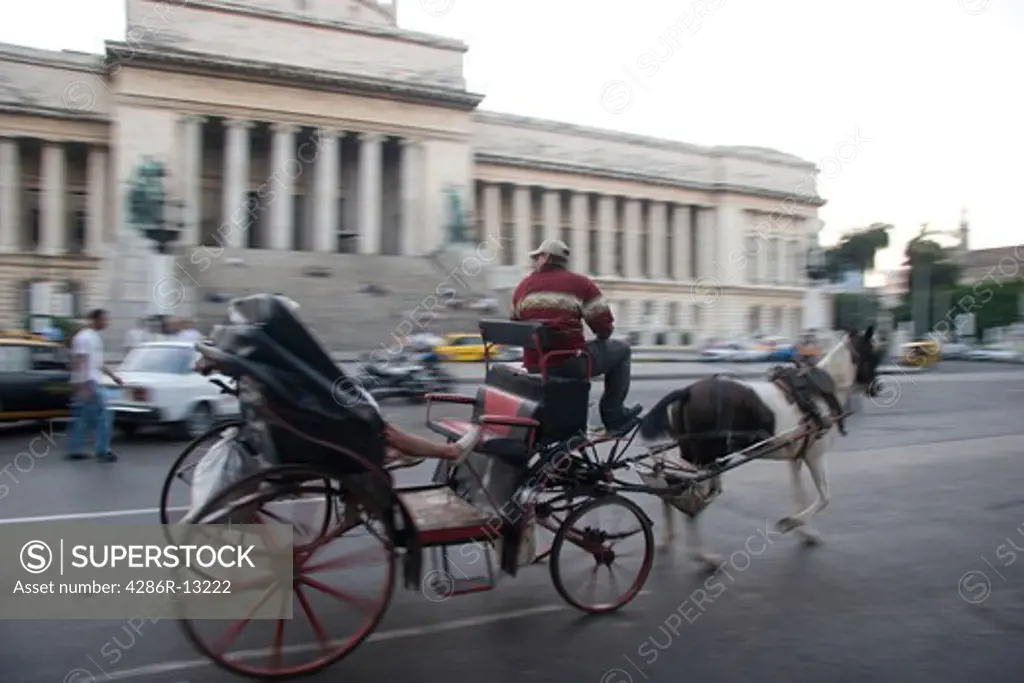 Horse and buggy in motion in front of the Capitolio in Old Havana