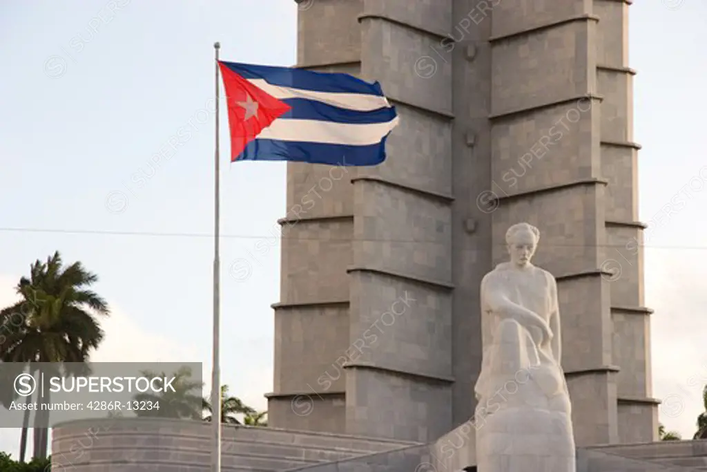 Backlit Cuban flag flies over statue of Jose Marti in front of Memorial tower at Plaza de la Revolucion, Havana Cuba