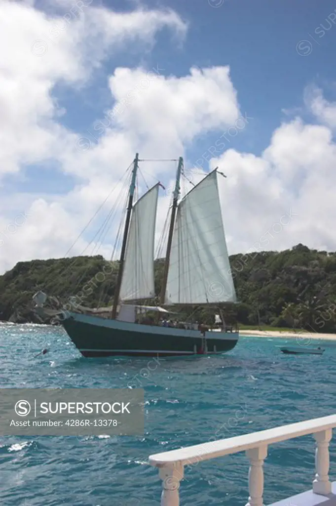 Two masted schooner pulls alongside with small island in the background - Tobago Cays