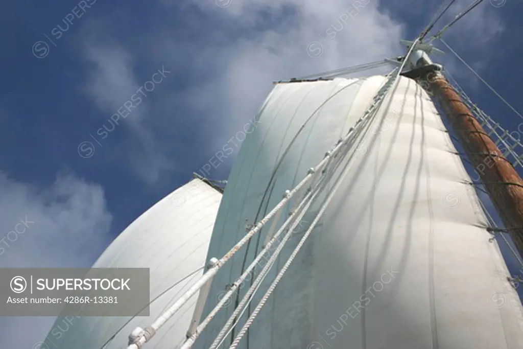 Majestic sails are full of wind against a mostly clear sky