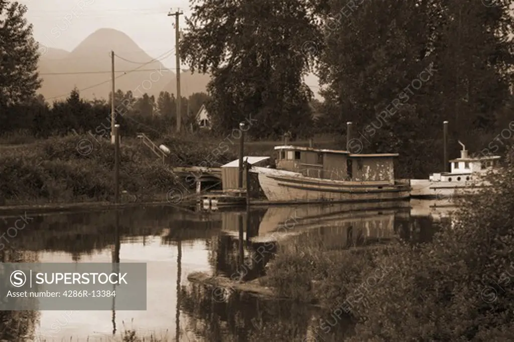 Old wooden boats anchored on Alouette River, Pitt Meadows BC - sepia toned
