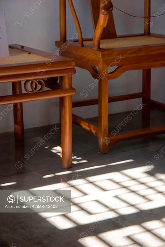 Ornate screen casts shadow onto tiled floor at foot of Ming Dynasty inspired chairs. Dr. Sun Yat-Sen Gardens, Vancouver Chinatown