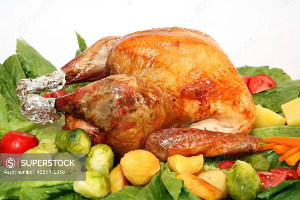 A festive turkey on a platter with an assortment of vegetables.