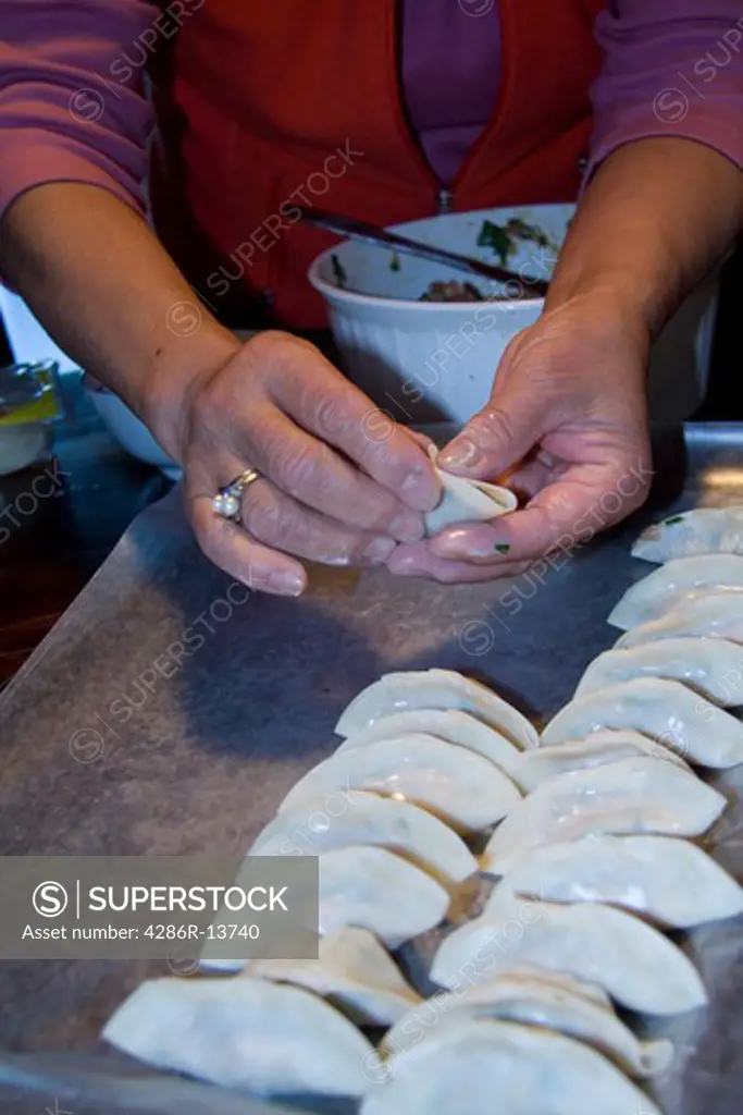 Chinese cook demonstrating how to make wor tip, also known as potstickers or pork dumplings. Correct folding technique is the key