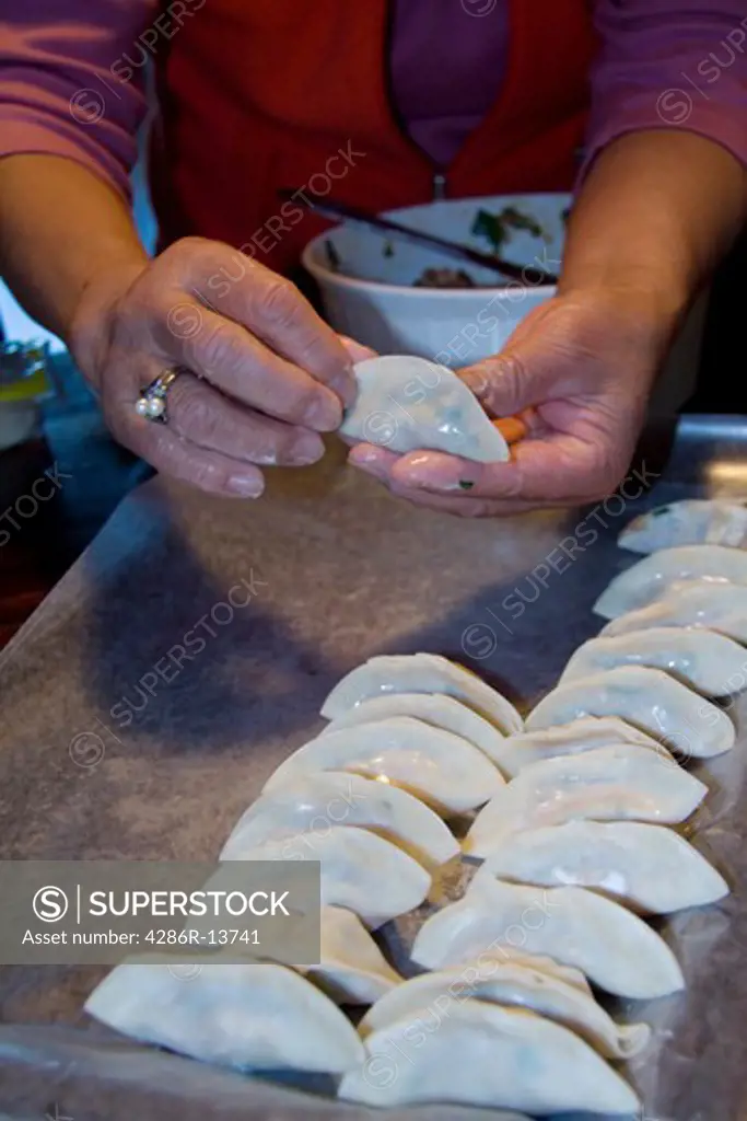 Chinese cook demonstrating how to make wor tip dumplings, also known as potstickers