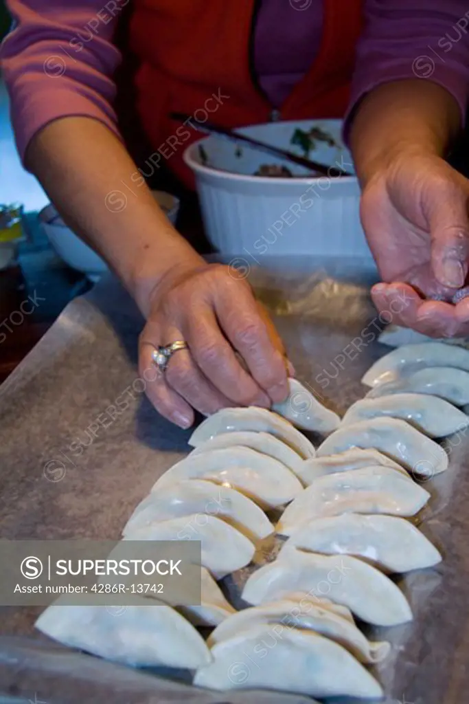 Chinese cook making tray of wor tip, also known as potstickers or pork dumplings