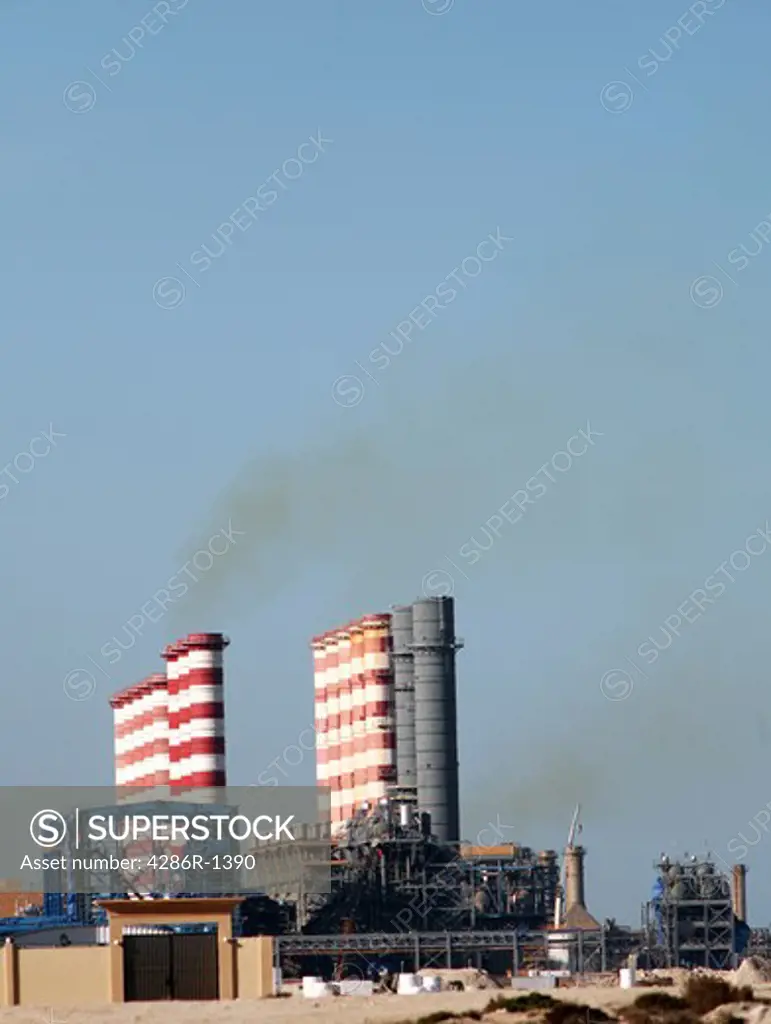 Smoke stacks on a desalination plant belching sulphurous fumes.