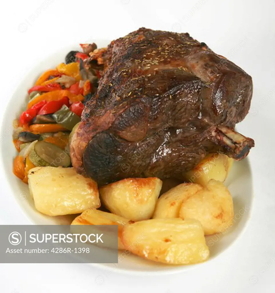 A leg of lamb with roast potatoes and stir-fried vegetables on a plate
