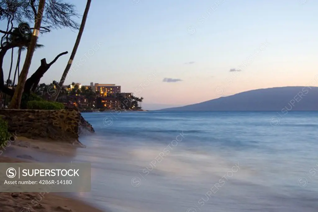 Magical view looking along the beach of West Maui, near Kahana, at dusk. Island of Lanai in the distance.
