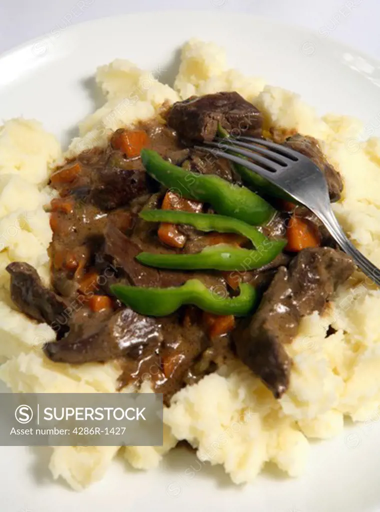 A meal of lamb's liver and onion stew (actually a stroganoff) with diced carrots served on a bed of creamed potato.