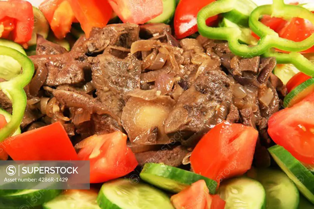 Fried liver and onions on a serving dish, garnished with salad.