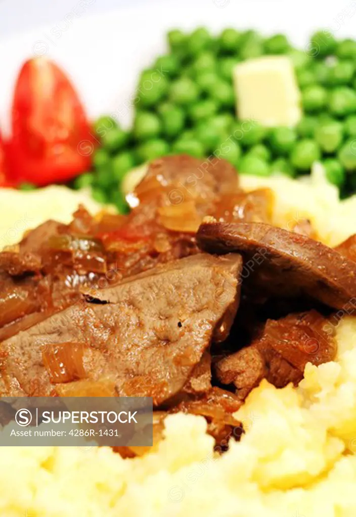 Stewed liver and onions on a bed of creamed potato, served with peas and tomato.