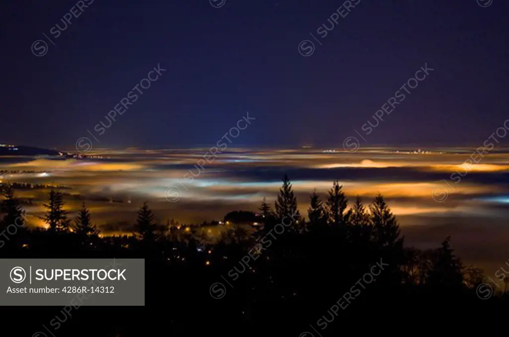 Up above Vancouver and the Fraser Valley shrouded in fog - Lights of the city cast colorful glows at night