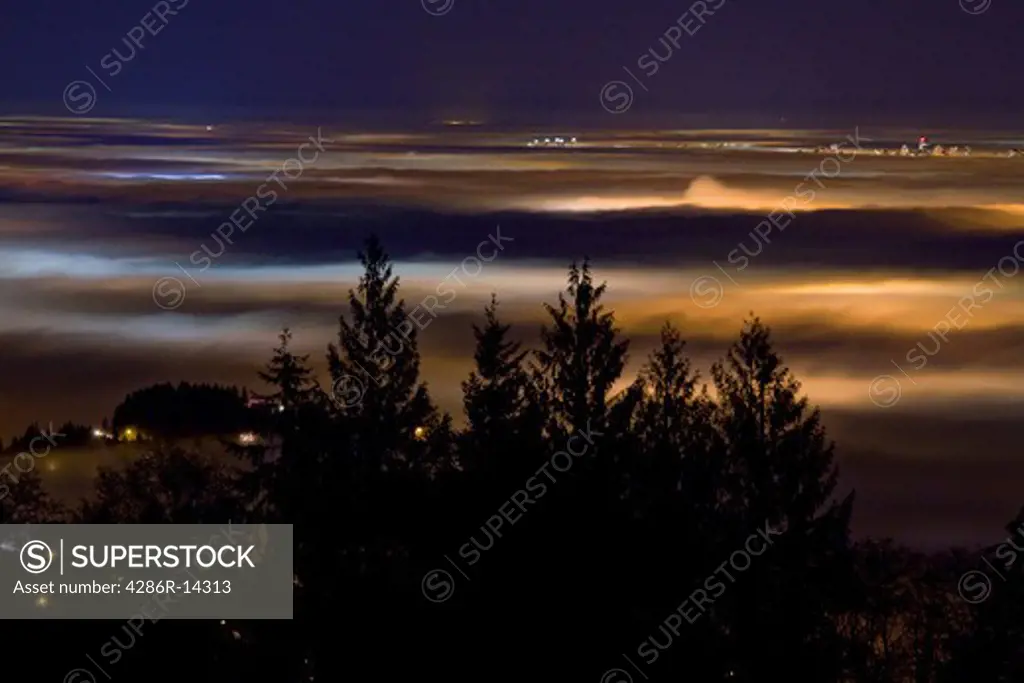 Vancouver and the Fraser Valley shrouded in fog - Lights of the city cast colorful glows at night, as seen from Cypress Mountain in West Vancouver