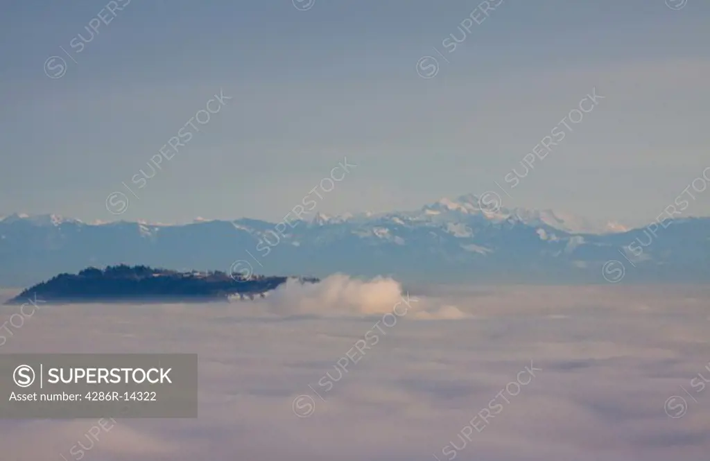 Vancouver and the Fraser Valley shrouded in fog - Simon Fraser University and Burnaby Mountain visible above the clouds. Cascade range in background.