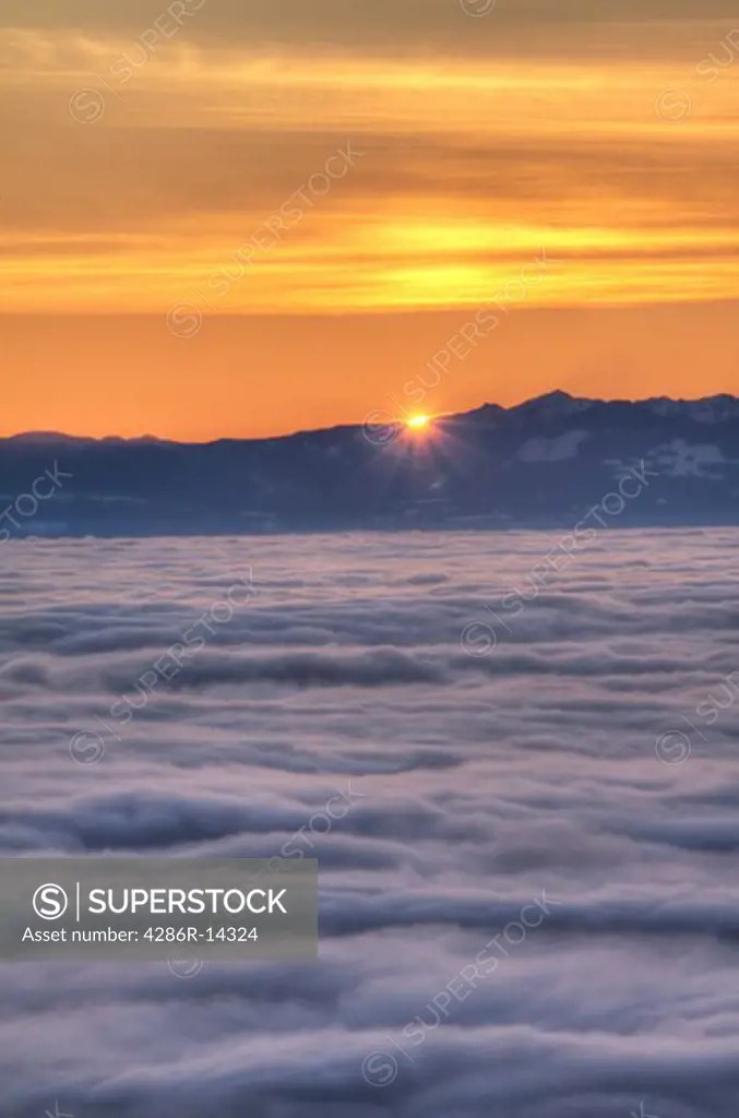 Sun sets behind Vancouver Island with fog over the Georgia Strait, as seen from Cypress Mountain in West Vancouver