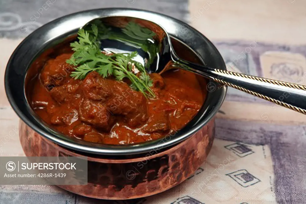 A serving bowl full of Madras butter beef curry.