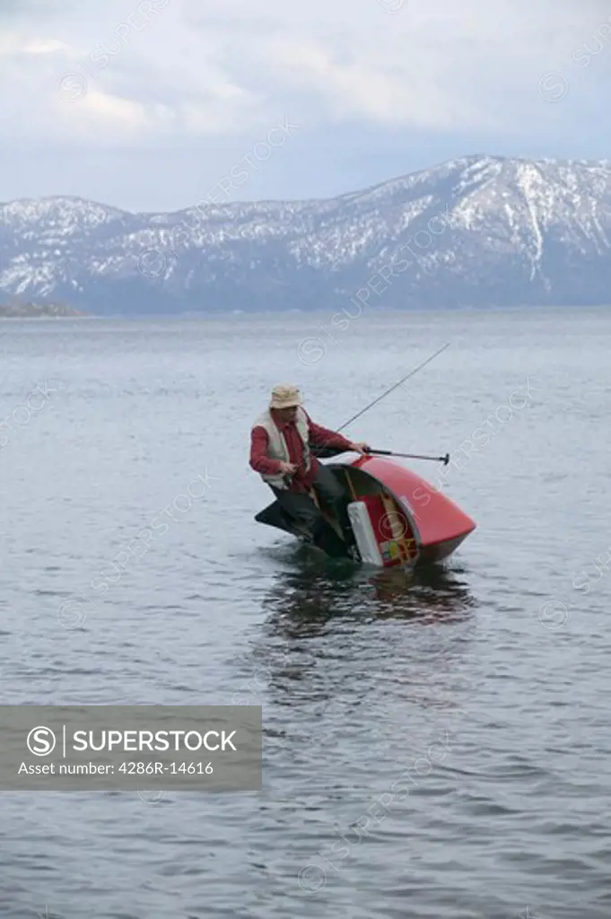 A fisherman tipping his canoe while canoing on Lake Tahoe, CA.