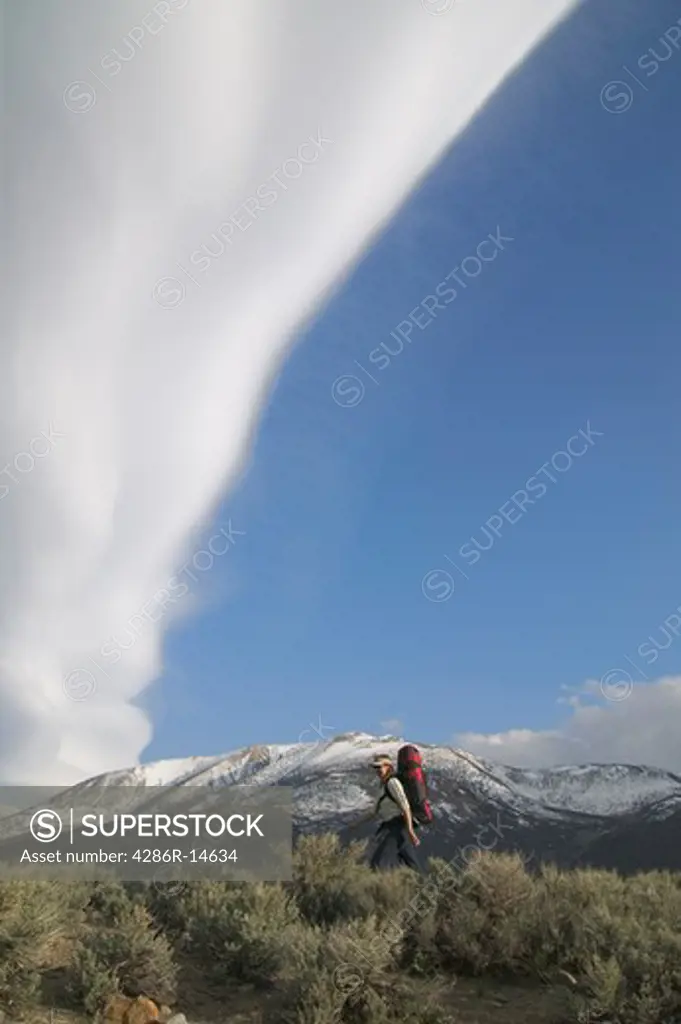 A woman hiking beneath a lenticular cloud near Crowley Lake in the Sierra mountains.