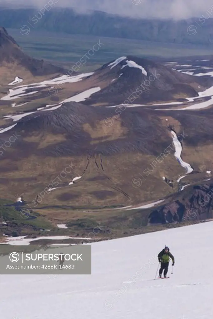 Two skiers climbing Mount Vsevidov in the Aleutian islands with the tundra below.