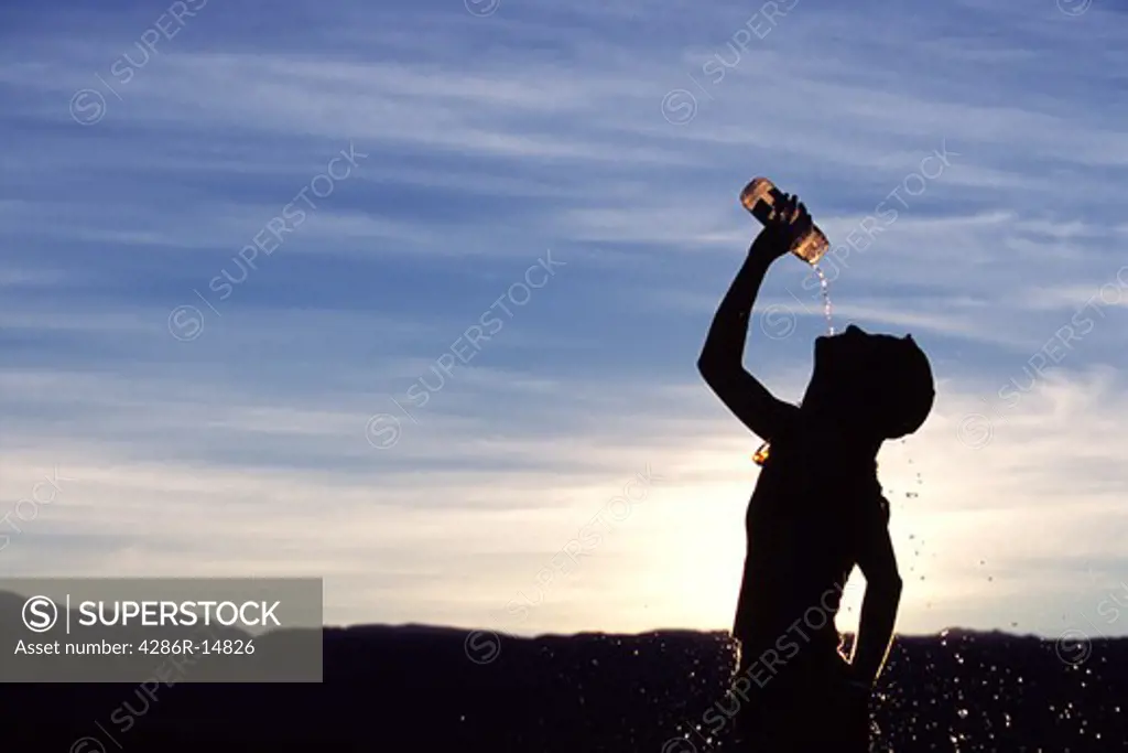 A woman pouring water onto her head after running.