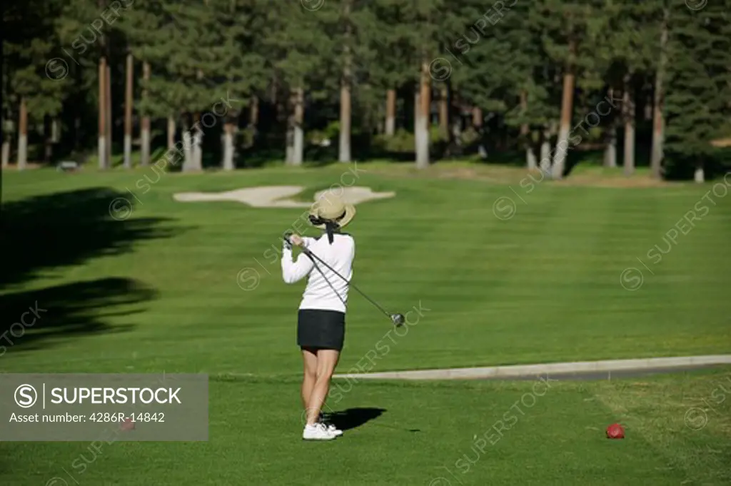 A woman teeing off while golfing at the Championship golf course in Incline Village, NV.