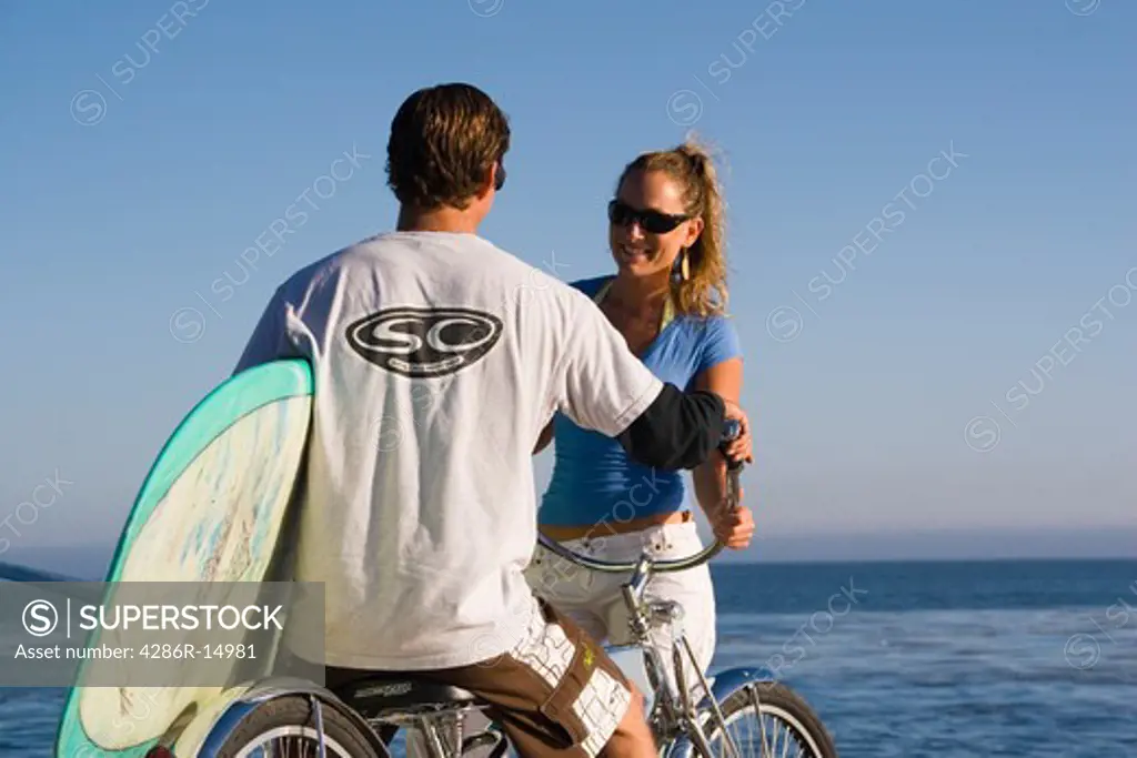 A couple with bikes and surfboards on a cliff above the ocean in Santa Cruz California
