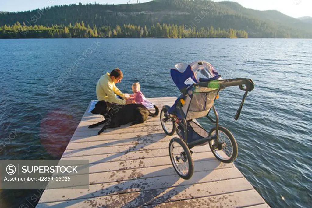 A father, child, and dog sitting on a dock in the sun at Donner Lake near Truckee California.