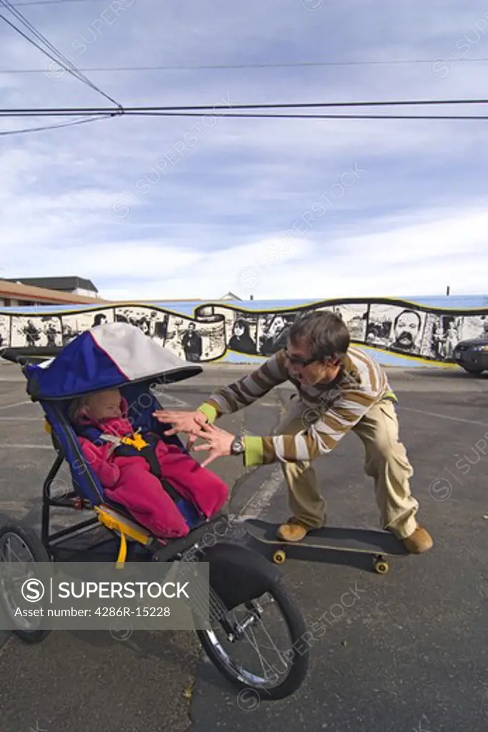 A man skateboarding with his baby in a stroller in Reno Nevada