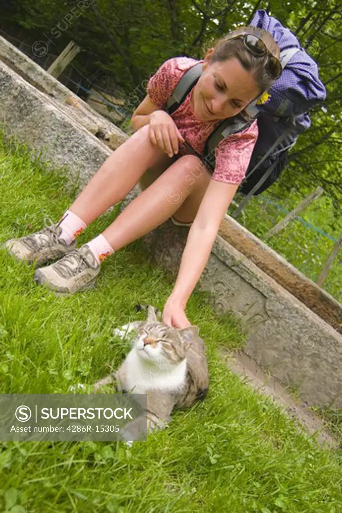 A woman petting a cat while hiking in France near the town of Les Houches