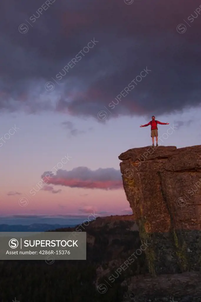 A man standing on the edge of a cliff at sunset above Lake Tahoe in California