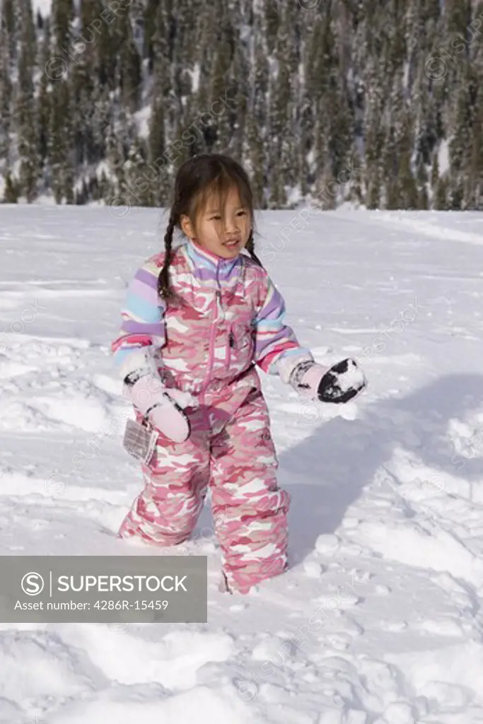 A young Korean girl throwing a snowball at Homewood ski area above Lake Tahoe California