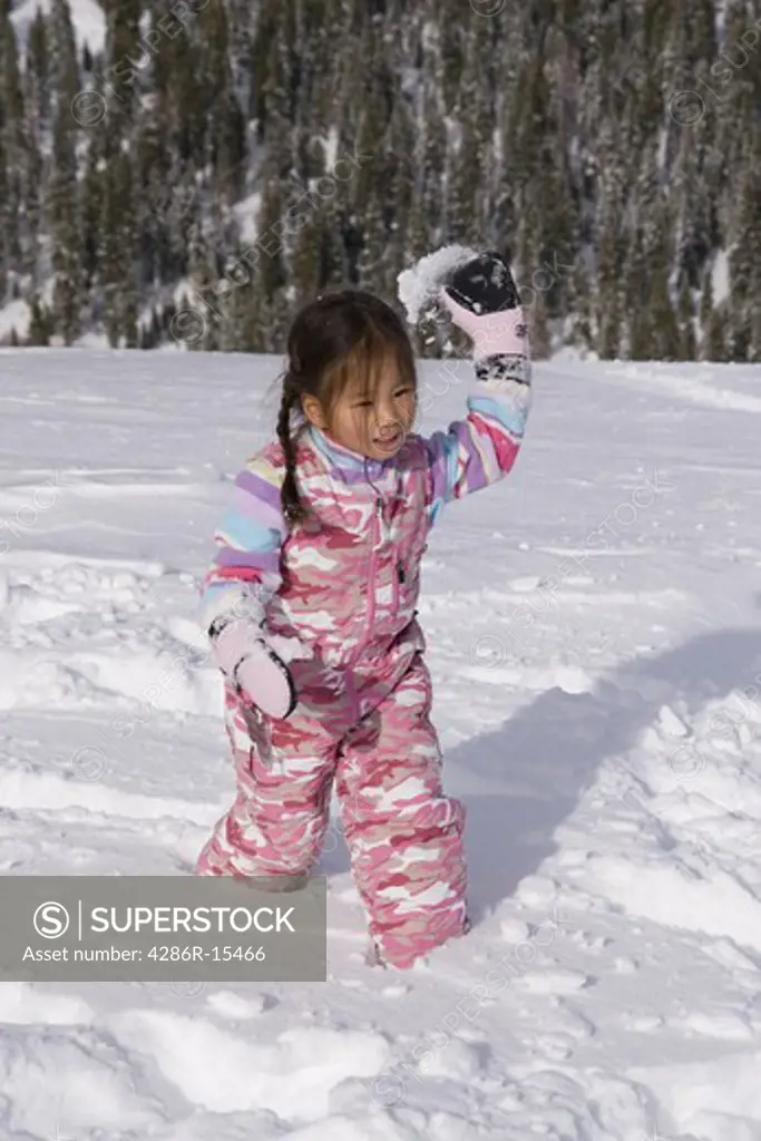 A young Korean girl throwing a snowball at Homewood ski area above Lake Tahoe California
