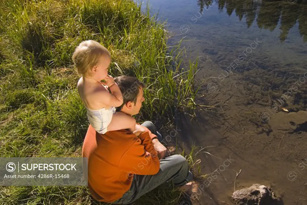 A baby sitting on her fathers shoulders by the Truckee River near Tahoe City California