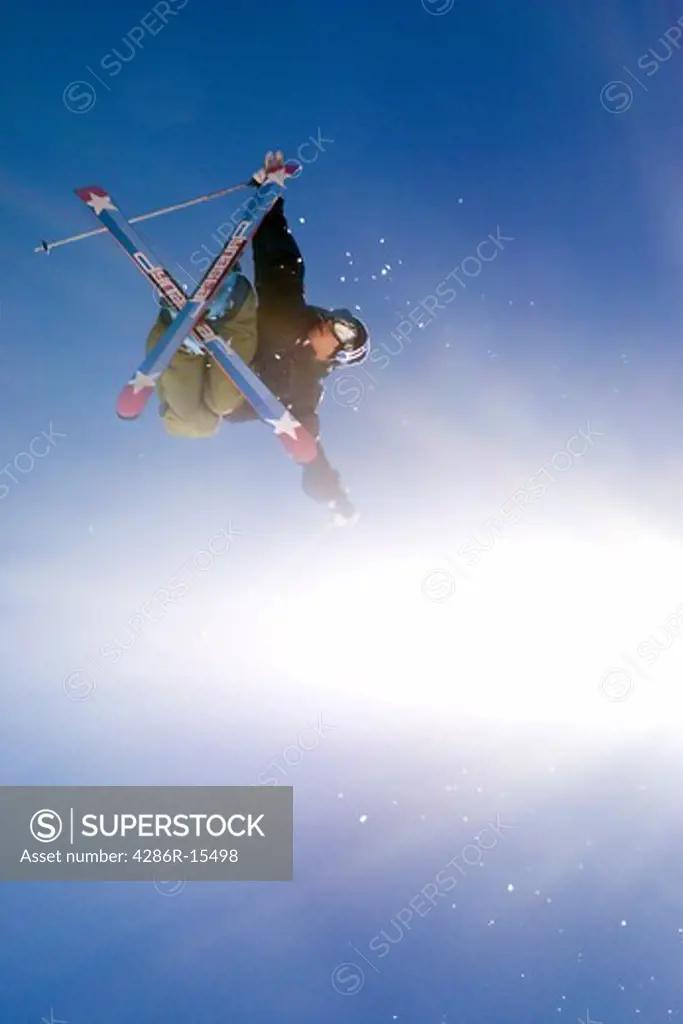 A skier jumping off a jump with a sunburst at Alpine Meadows in California