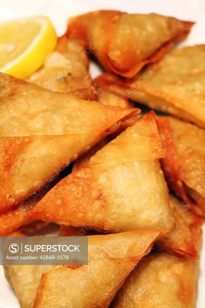 Samosas with a lemon slice. The fried pastries - containing vegetable or meat filling - are popular in Arabia and Asia.