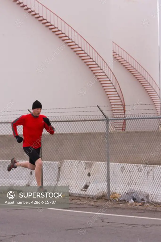A man running past oil storage tanks in Reno in Nevada