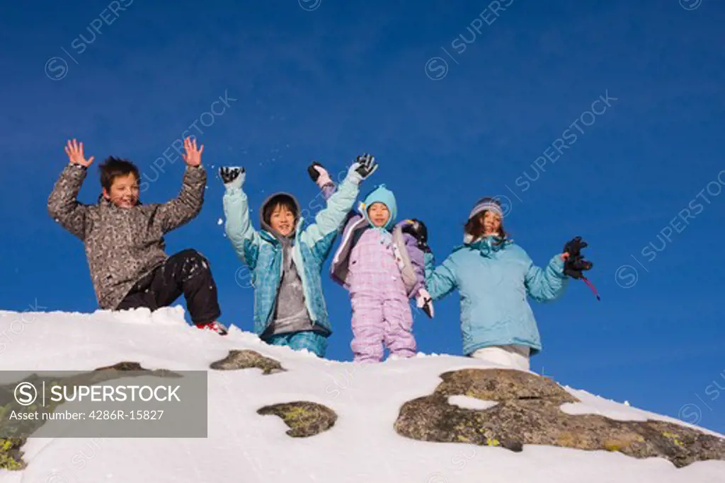 Four children standing on top of a snowy rock at Sierra at Tahoe ski resort near Lake Tahoe in California
