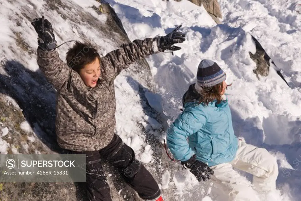 A girl and boy sliding off a snowy rock at Sierra at Tahoe ski resort near Lake Tahoe in California