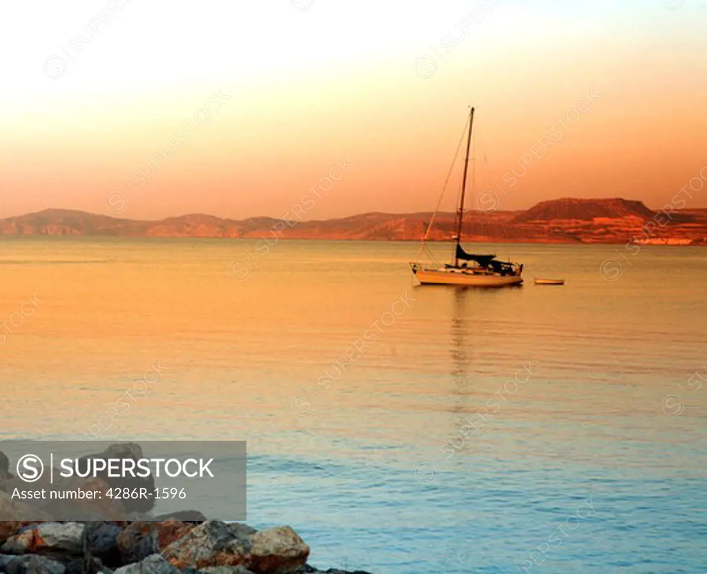 Sunset over Sitia Bay, Crete, with a small yacht and tender.
