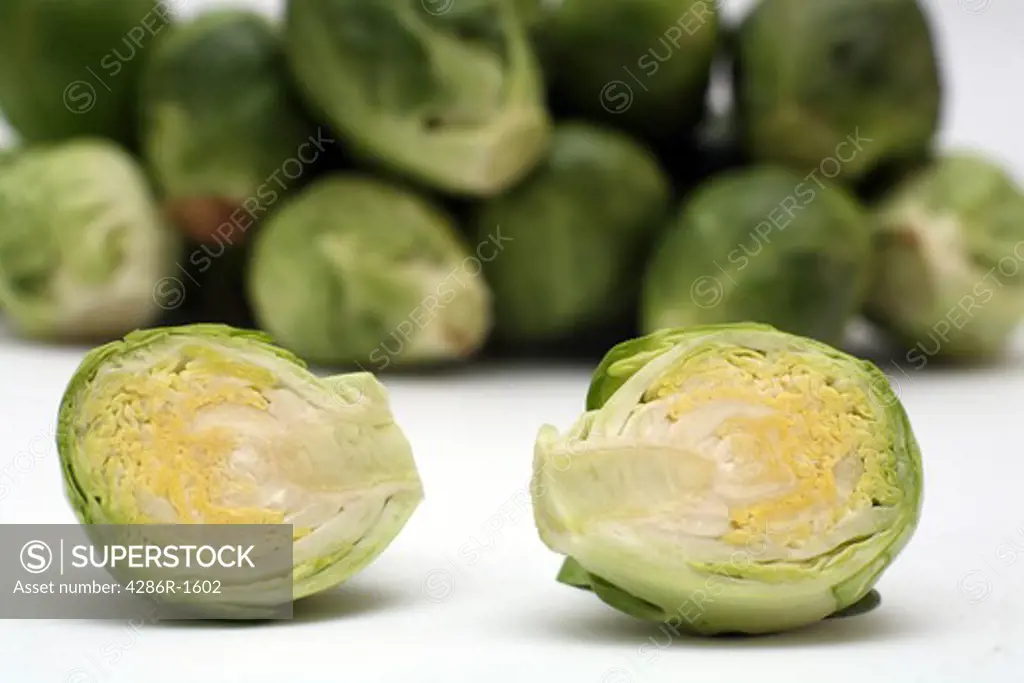 A sliced brussels sprout, macro view, in front of a pile of other sprouts