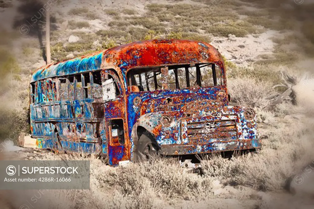 A psychedelic  old bus that has been shot full of bullet holes at a shooting range near Truckee in California