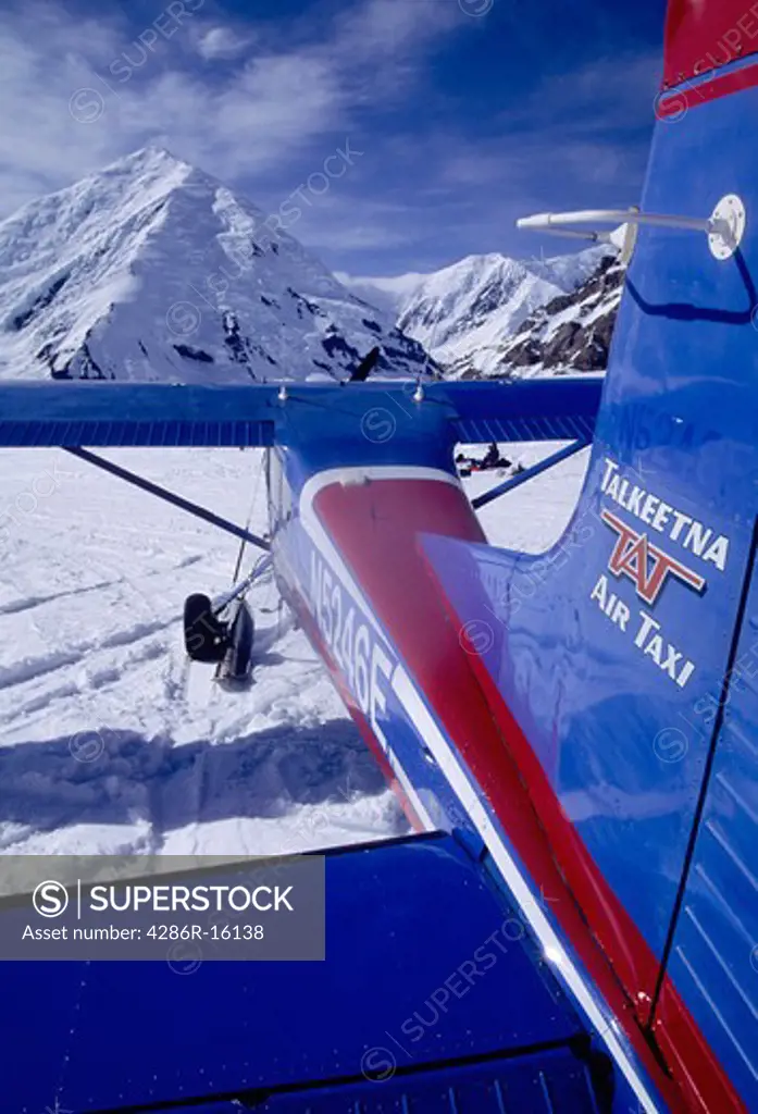 A blue and red bush plane on skis on the Kahiltna Glacier in the Alaska Range near Denali in Alaska