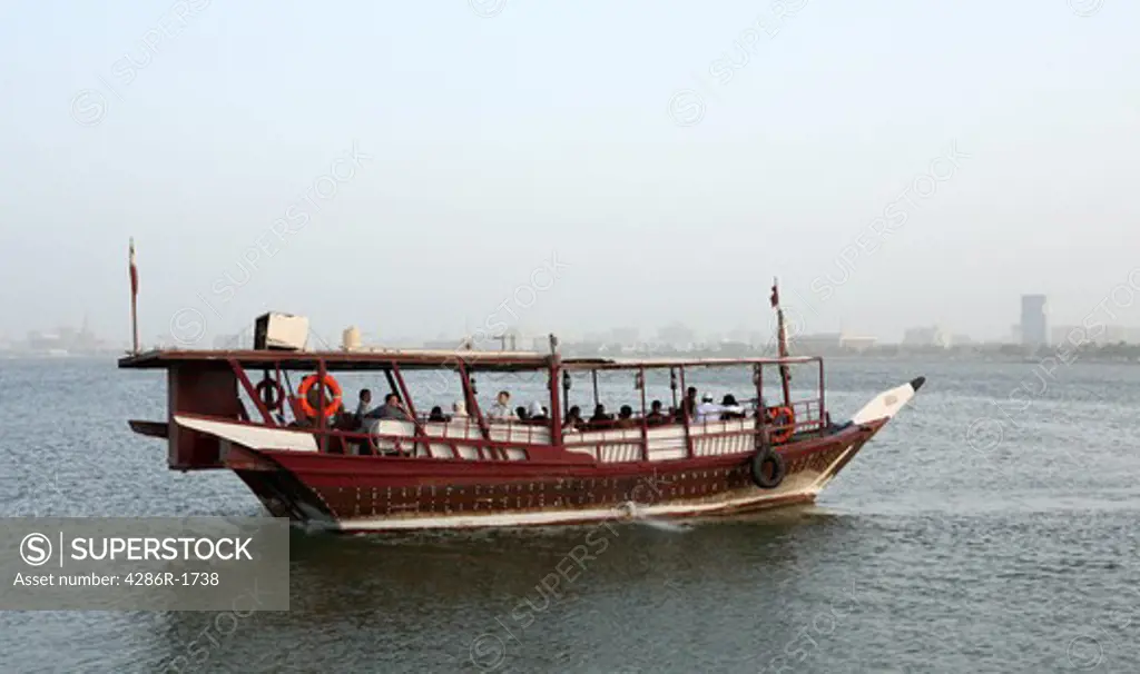 A traditional dhow takes families on a trip around Doha Bay, Qatar, during the Eid al Fitr holiday, October 2, 2008. The Doha city centre skyline, with the Emiri Diwan palace and government officies is in the background.