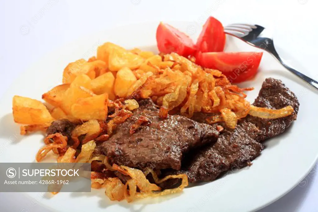 Traditional Austrian zweibelrostbraten, beef escalope with crispy fried onions, served with diced deep fried potatoes. The easily made meal is popular in Central European countries including Austria and Hungary.