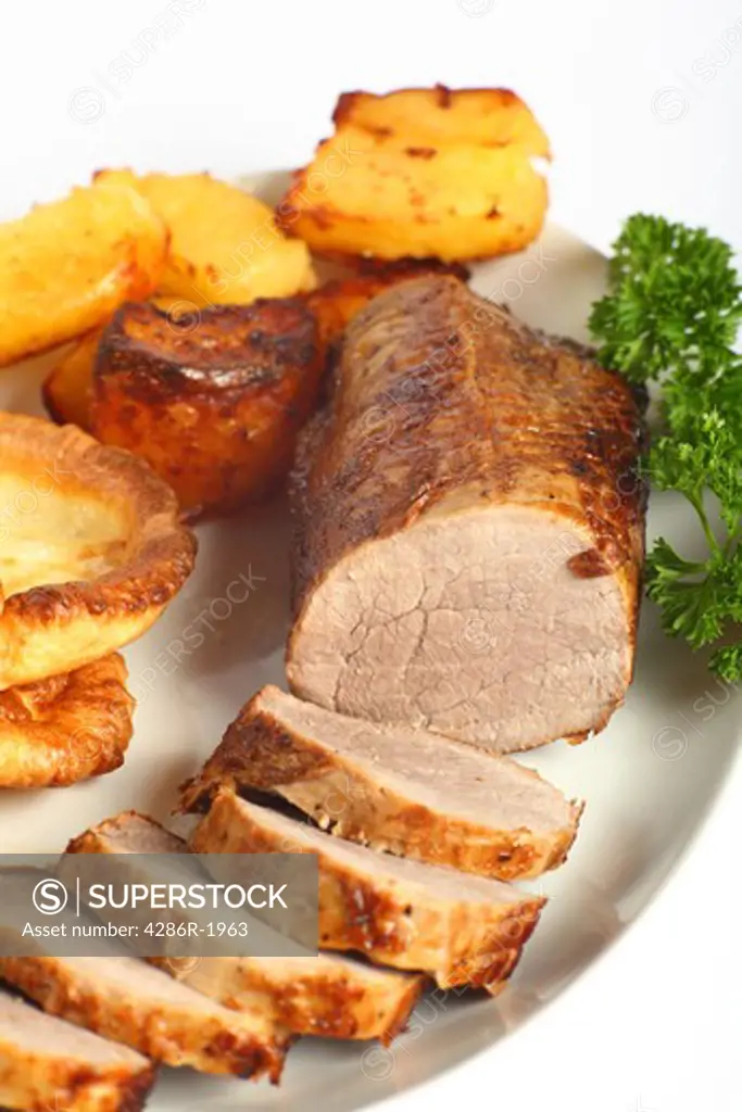 A beef 'eye roast' joint, sliced into medallions, on a plate with roast potatoes and Yorkshire puddings.
