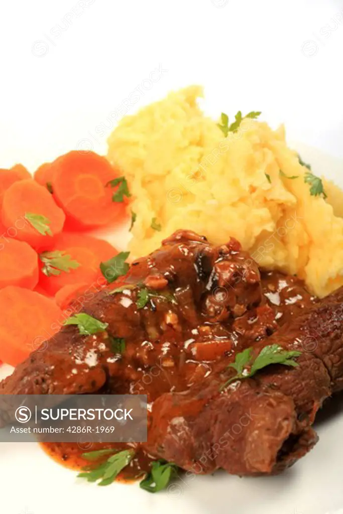 A meal of traditional British stuffed 'beef olive' escalopes served with mashed potatoes and boiled carrots, vertical